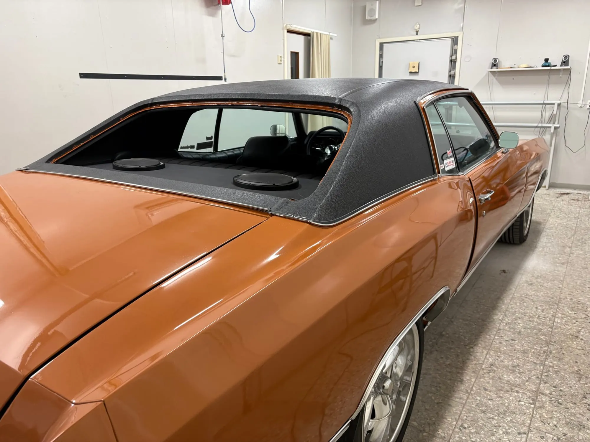 Orange bil med svart vinyltak, sedd snett bakifrån